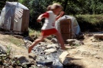 Greek Spas, Smokovo area:A girl jumps over stream waiting her grandmother who takes a warm & natural spring bath full of sulphur, into the handmade shanty.
 © Maro Kouri