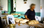 Greece, Amorgos. Old woman makes bread. The photograph of her child‘s wedding is always on her table. © Maro Kouri