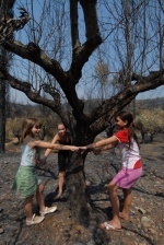 Greece, Peloponese, prefecture of Messinia, Kalyvia: Aliki, Rafaela and Mary Kourou play on the burning land, trying to forget the horrible moments they had when the ‘sea of fire‘ showed up. © Maro Kouri