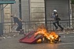 Riots during a rally against plans for new austerity measures///Protester hunted by a riot policeman in  front of a burning garbage bin
 © Maro Kouri
