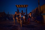 July 5, 2011. Botanikos, Athens, Greece:The night falls in the slum. Instead of going to sleep, the three little Roma boys drive an open truck where they carry  collected cables and scrups in order to sell
 © Maro Kouri