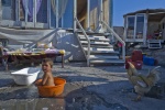 September 16, 2011-Athens, Greece: Baby has a bath into a small plastic basin next to a cock outside his family shanty 
 © Maro Kouri