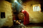 India. Fatima cooks for her family. The picture of the empty room with the metallic and wooden utensils beside the cooking fire, suggests the saying of the Hindu mystics, «the material world is an illusion of life». Fatima, a swaying silhouette in a silk sari, greets us. The dish she is preparing has captured our senses. © Maro Kouri