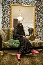 Abu Dhabi: Woman in a shopping mall, tries luxury accessories made by famous couturier. Under the silk, parfumed nigab she wears an expensive suits that she shows it only in house. Women from south Asian countries came to live under horrible situation in the same country, to work hard and sent money to their poor families
 © Maro Kouri